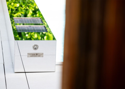 Coverseal-landscape5 Habillage effet miroir de la Coverseal avec finition inox polie reflétant la végétation, équipé de panneaux solaires intégrés pour l’alimentation.