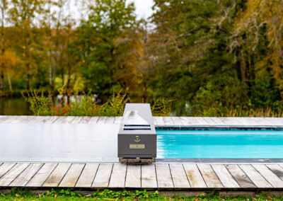 Pond2 Piscine avec couverture Coverseal partiellement ouverte laissant apparaître une eau turquoise, dans un cadre naturel boisé.